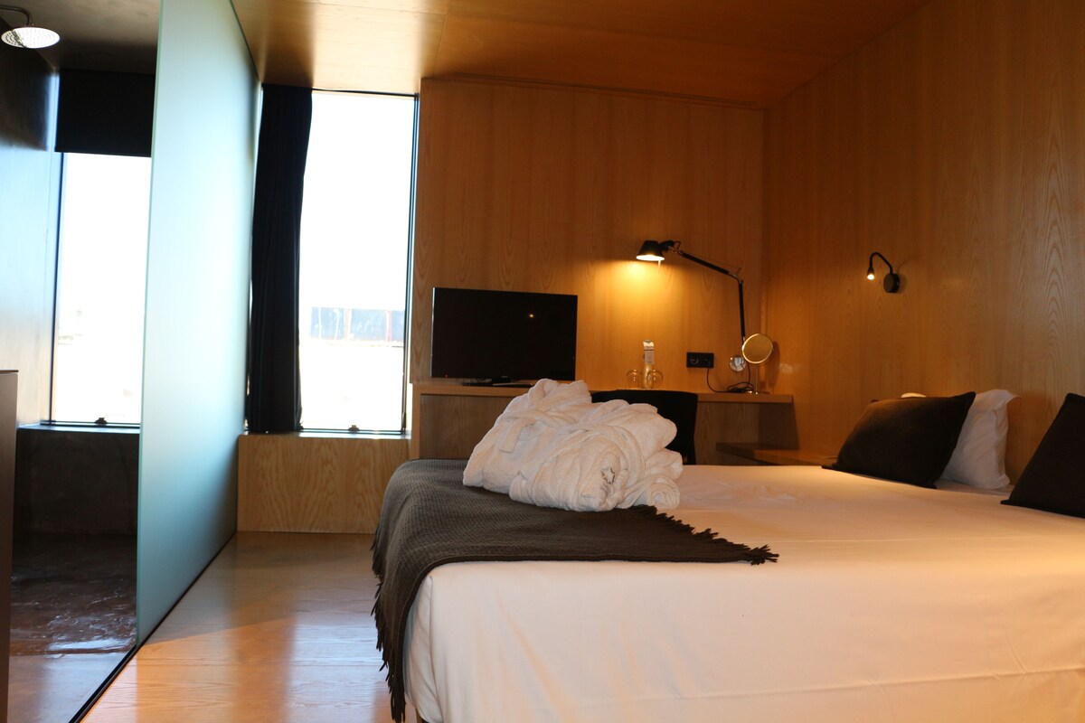Een hotelkamer met een bed, een televisie, een bedlamp en een raam.