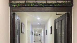A hallway with a modern design, featuring a patterned ceiling, framed pictures on the walls, and a fire extinguisher on the floor. - Taipei Happy Home (Taipei)