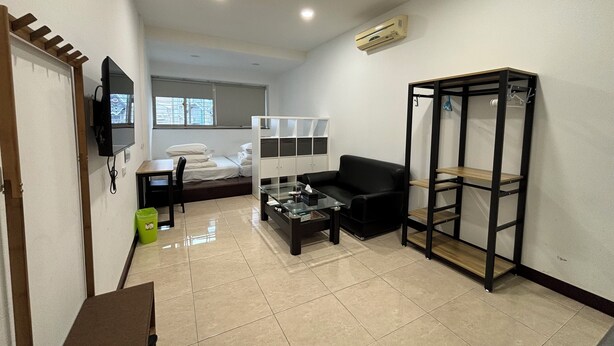A compact living space with a bed, a sofa, a coffee table, a TV, and a built-in wardrobe. - Taipei Happy Home (Taipei)