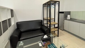 A compact kitchenette with a black sofa, a small coffee table, and a glass-top table with a tissue box and remote control. - Taipei Happy Home (Taipei)
