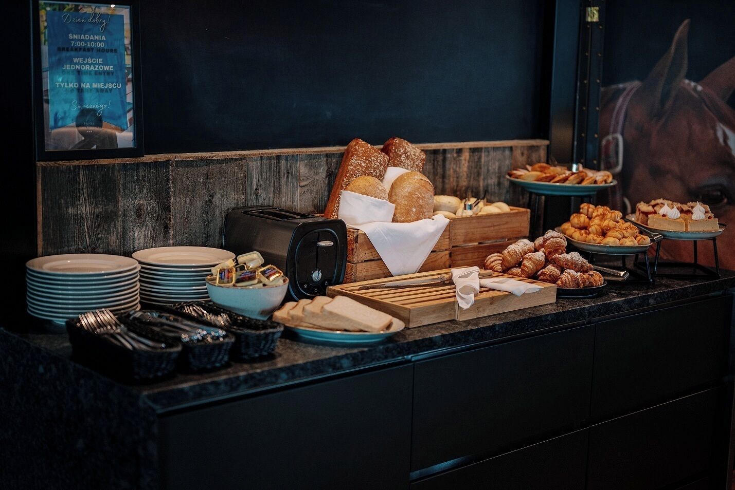 A breakfast buffet with various breads, pastries, and a toaster.