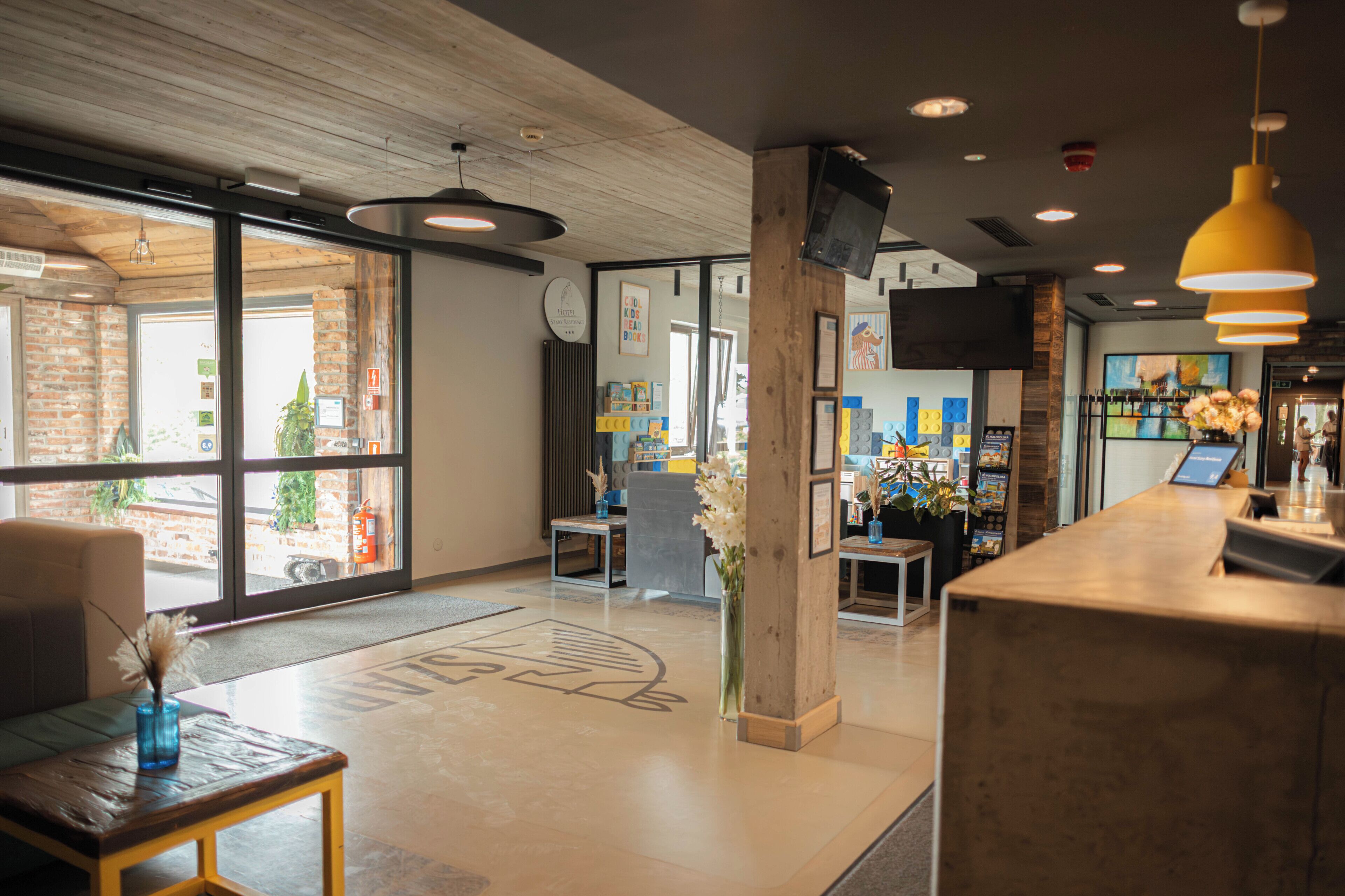 Un hall de hotel con mostrador de recepción, zona de estar y grandes ventanales con vistas al exterior.