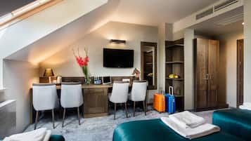 Una habitación de hotel moderna con techo estilo loft, un escritorio con sillas, un televisor de pantalla plana, un armario y dos camas.