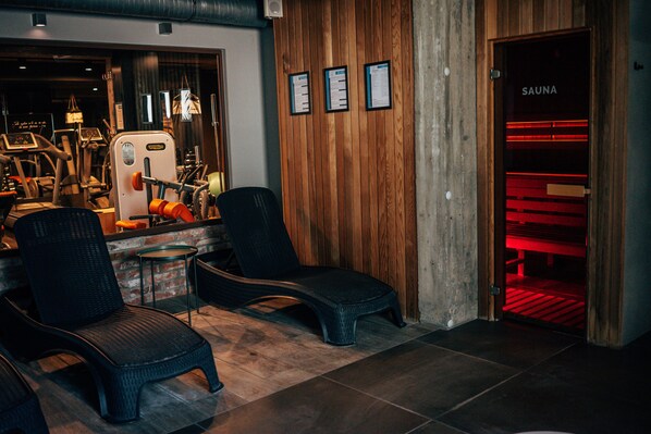 A spa area with wooden walls, a sauna, and exercise equipment. - Hotel Szary Residence (Michalowice)