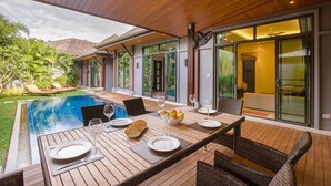 An outdoor dining area with a pool, wicker furniture, and a view of the house. - Saiyuan Estate by TropicLook (Rawai)