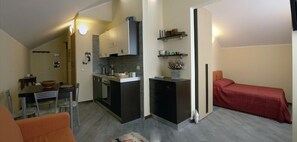 Un espace de vie compact comprenant un coin cuisine, un coin repas et un lit.