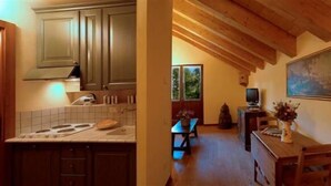 Une cuisine avec des meubles de rangement en bois, un pare-feu en carrelage et un coin repas comprenant une table et des chaises.