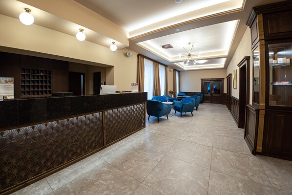 A hotel lobby with a reception desk, blue seating area, and a chandelier. - Wellness Hotel Pivovar Monopol (Teplice)