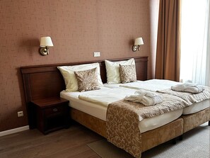 A hotel room with a large bed, two bedside tables, and two wall-mounted lamps. - Wellness Hotel Pivovar Monopol (Teplice)