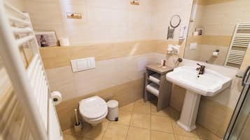 Et badeværelse med toilet, vask og brusebad.