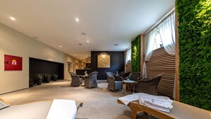 A spa area with wicker furniture, a wooden bench, and a green wall.