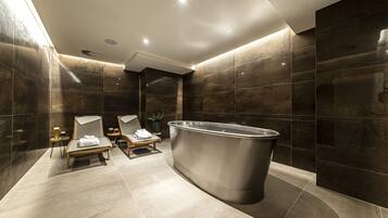 Relax in a spacious bathroom with a bathtub and sleek, dark tile surroundings.