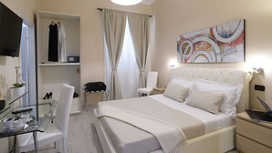A hotel room with a bed, a desk with a laptop, a chair, a wardrobe, and a painting on the wall. - Town House 57 (Rome)