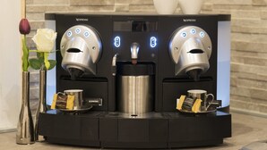 A Nespresso coffee machine with two dispensers, a coffee pot, and a cup holder. - Town House 57 (Rome)