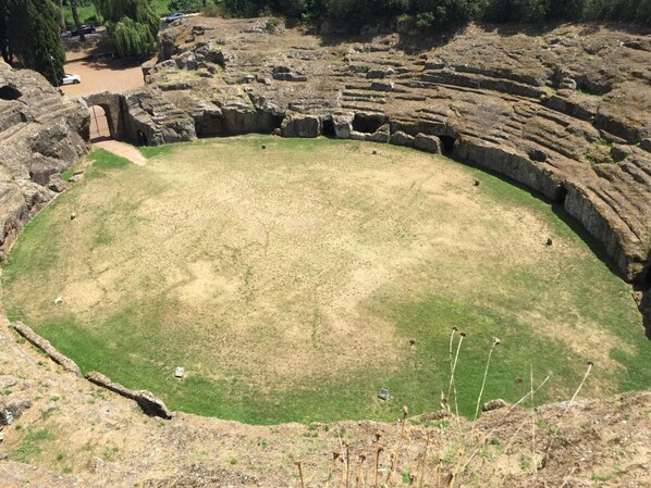 An ancient amphitheater with a grassy central area and stone seating.