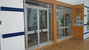 A hallway with large glass doors, wooden flooring, and a sign indicating a residential unit. - Residencial S. Gião (Valenca)