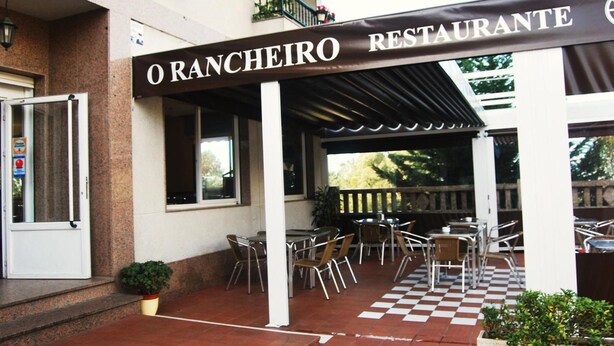 An outdoor patio area with tables and chairs, a checkered floor, and a sign reading "O RANCHEIRO RESTAURANTE". - Hostal O Rancheiro (Vigo)