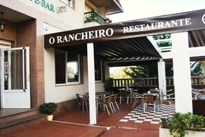 Un área de patio al aire libre con mesas y sillas, un piso a cuadros y un letrero que dice "O RANCHEIRO RESTAURANTE".