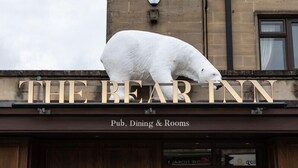 A building with a large white polar bear sculpture on top and the sign "THE BEAR INN" below. - Bear Hotel (Bath)