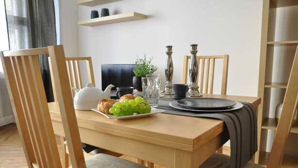 A dining table set with a plate of grapes, a croissant, and a glass of water. - Metropolis Prague Apartments (Prague)