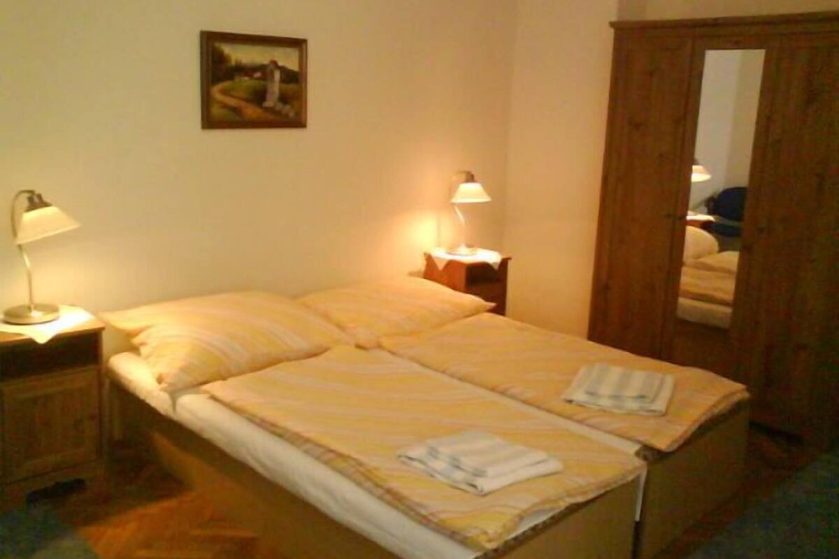 A double bed with two bedside tables, each with a lamp. A painting hangs on the wall above the bed.