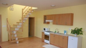 A kitchen with wooden cabinets, a microwave, a stove, and a refrigerator. - Apartmany Bratislava (Bratislava)