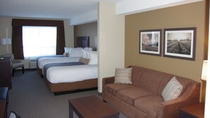 A hotel room with two beds, a sofa, a desk, and a TV.
