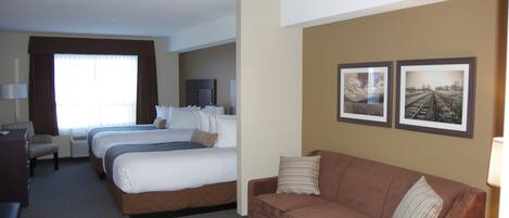 A hotel room with two beds, a sofa, a desk, and a TV.