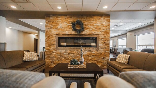 A lobby with a stone fireplace, two sofas, a coffee table, and a television screen.