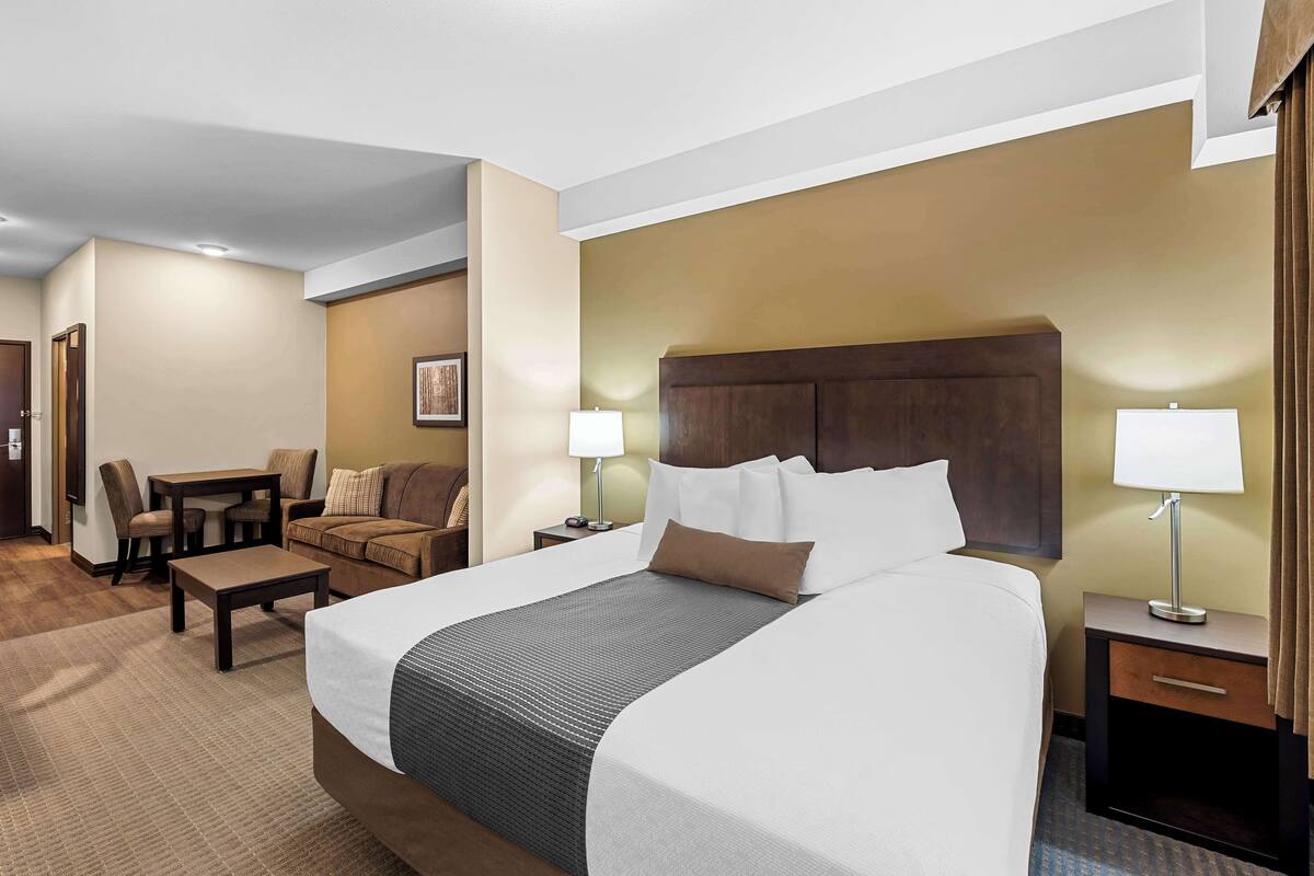 Ein Hotelzimmer mit einem großen Bett, einem Schreibtisch, einem Stuhl und zwei Nachttischen mit Lampen.