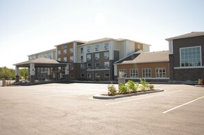 Ein mehrgeschossiges Hotel mit Parkplatz davor.