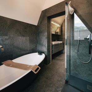 A modern bathroom with a bathtub, a shower, and a vanity with a mirror.