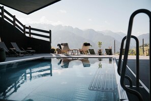 Un espace piscine avec des chaises longues et une vue sur les montagnes.