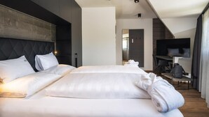A hotel room with a large bed, a flat-screen TV, and a seating area with a table and chairs.
