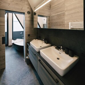 Une salle de bain moderne avec deux lavabos, un grand miroir et une vue sur un balcon.
