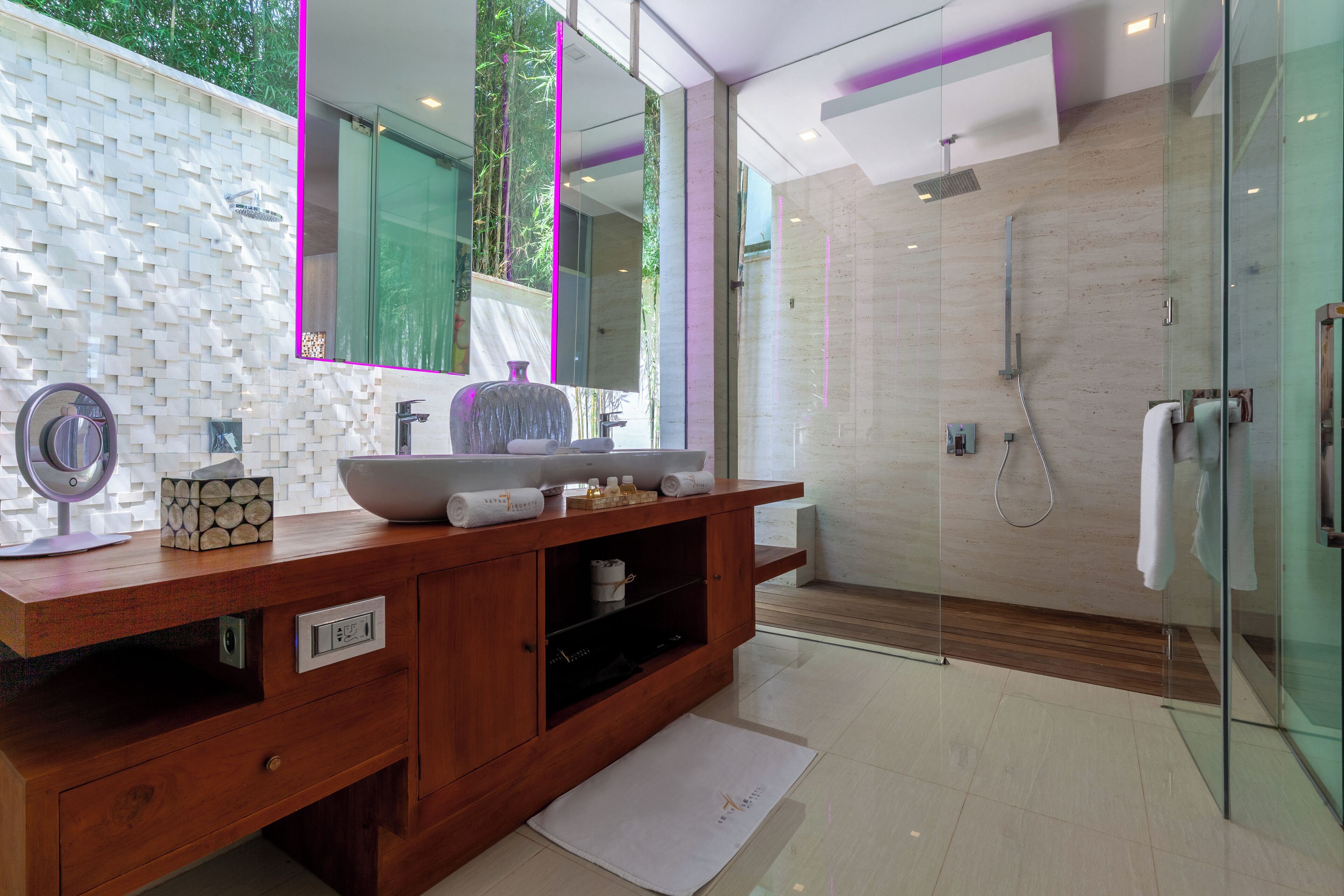 A modern bathroom with a wooden vanity, a large mirror, and a glass shower enclosure.