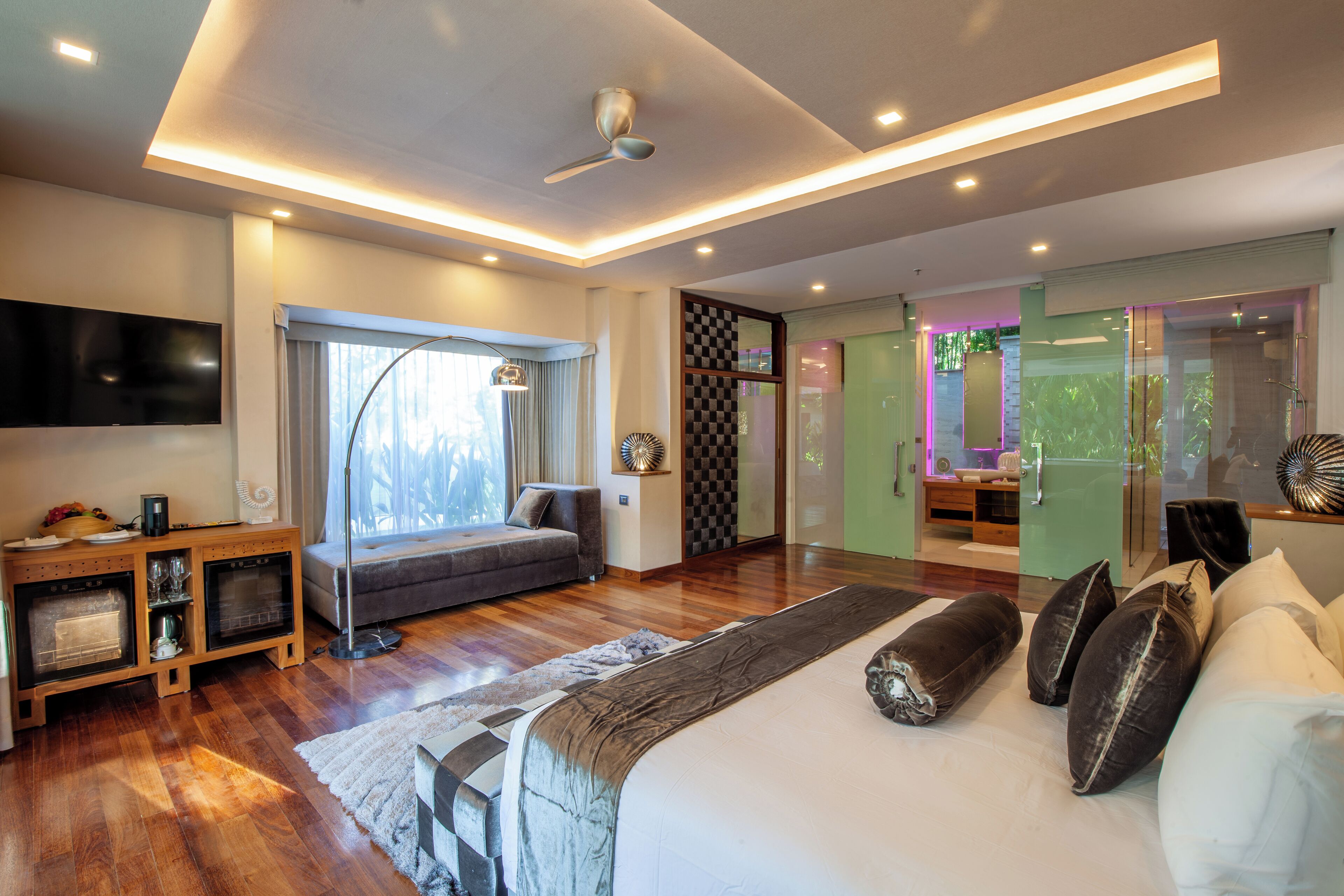 Un dormitorio moderno con una cama grande, televisor, chimenea y puerta corrediza de vidrio que da a un baño.