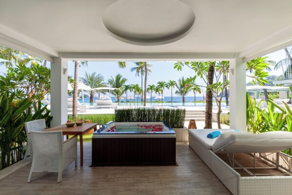 Una habitación con vistas al mar, bañera de hidromasaje, una mesa de comedor y un sofá.