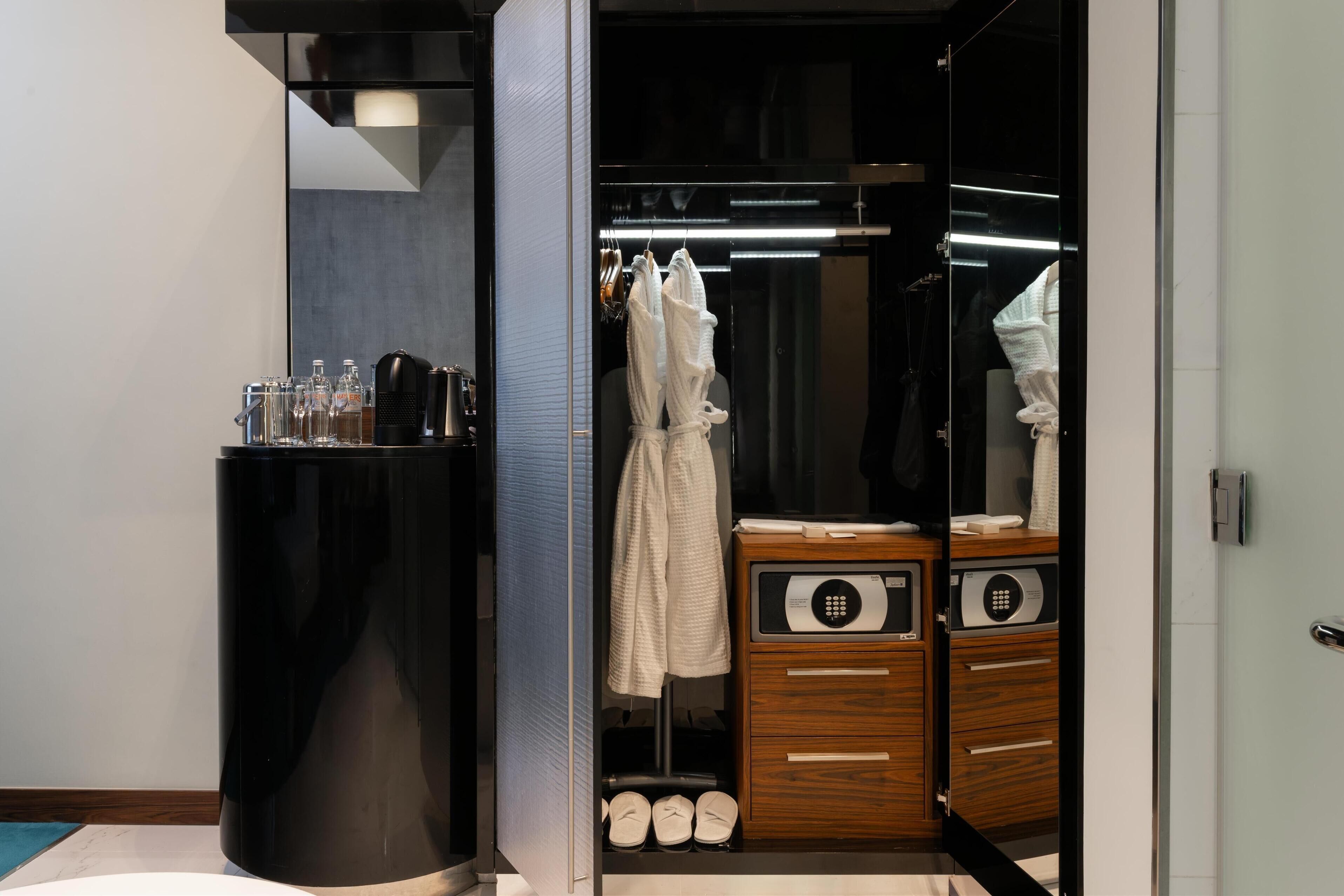 A modern bathroom with a black vanity, a glass shower enclosure, and a wooden cabinet with a built-in microwave.