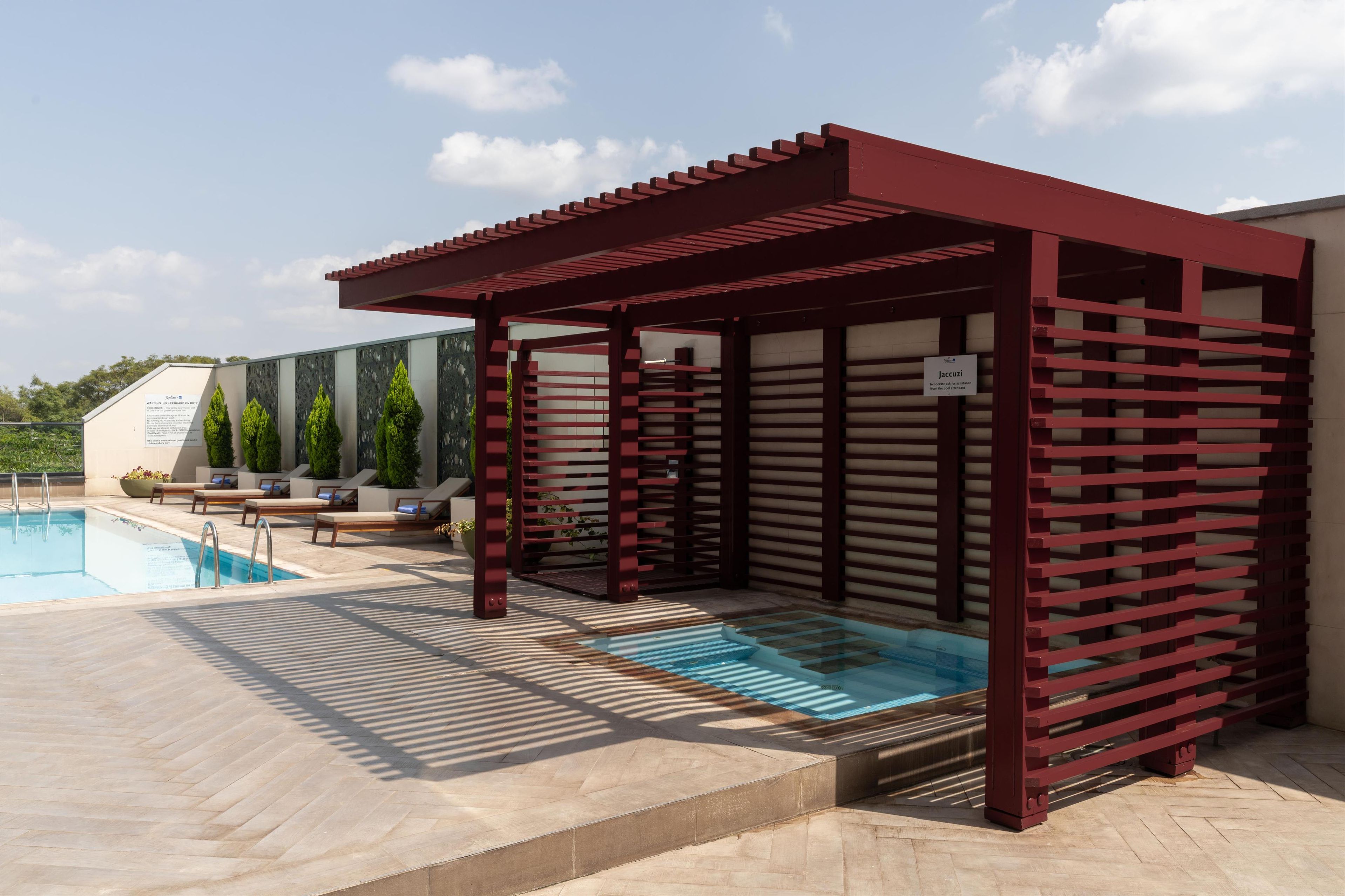 A pool area with a red pergola, lounge chairs, and a sign indicating a spa.