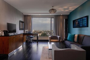 A modern hotel room with a large window, a flat-screen TV, a wooden cabinet, a sofa, and a dining area. - Radisson Blu Hotel Nairobi Upper Hill (Nairobi)