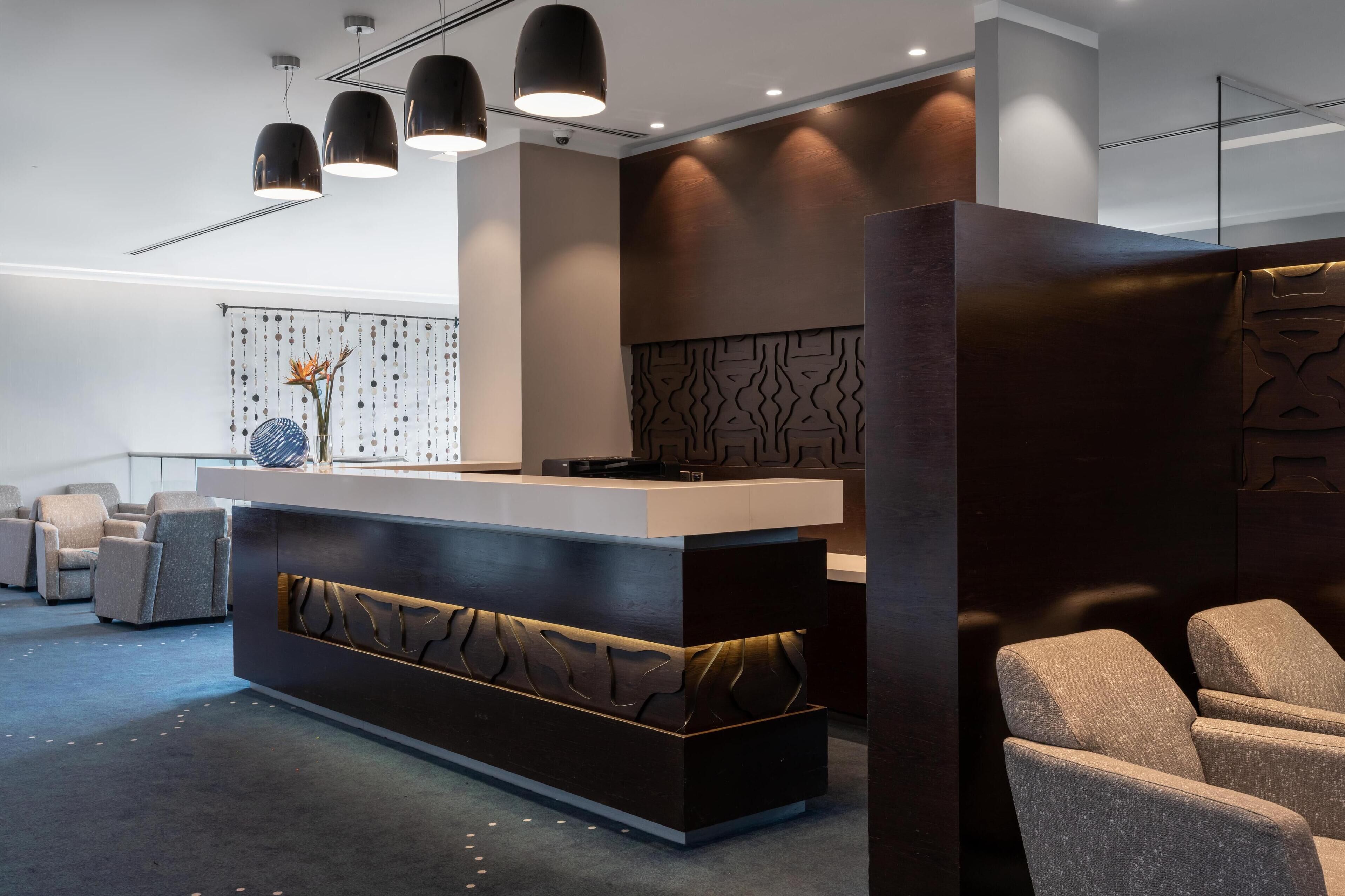 A reception area with a modern design, featuring a reception desk, seating area, and decorative wall panels.
