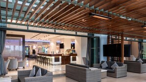 Een ruime lobby met rieten banken, een bar en een groot televisiescherm.