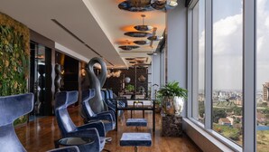 Een modern interieur met een lange rij blauwe stoelen, een houten vloer en grote ramen met uitzicht op de stad.