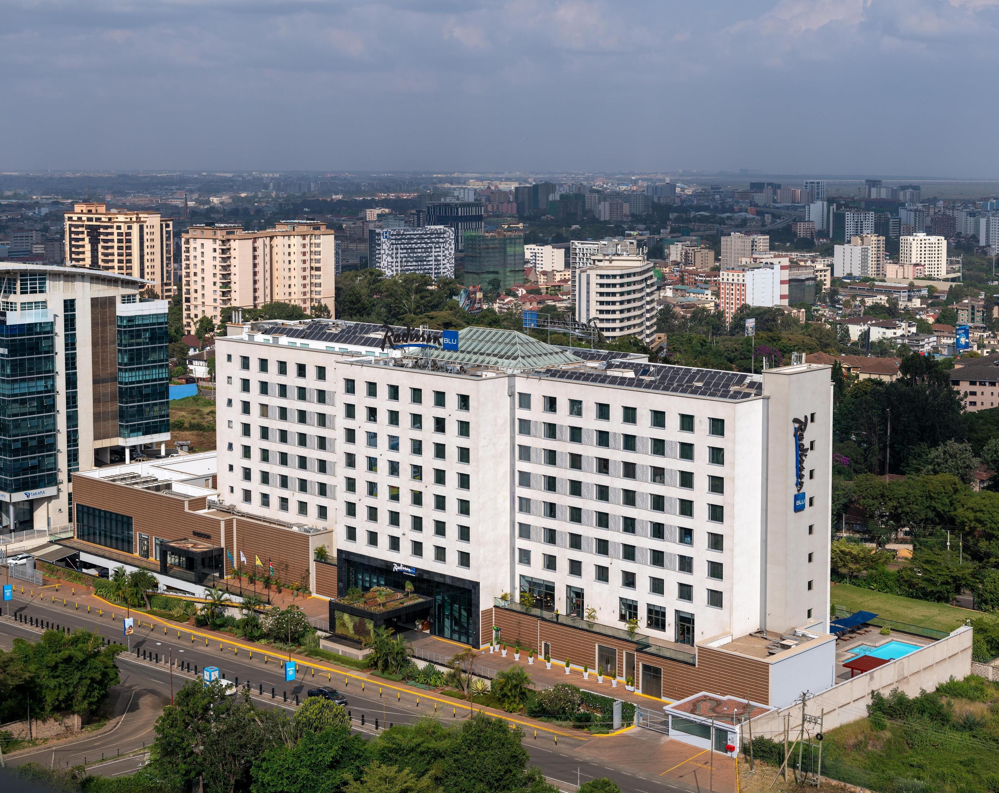 A multi-story hotel with a modern design, featuring a central courtyard with greenery and a swimming pool.