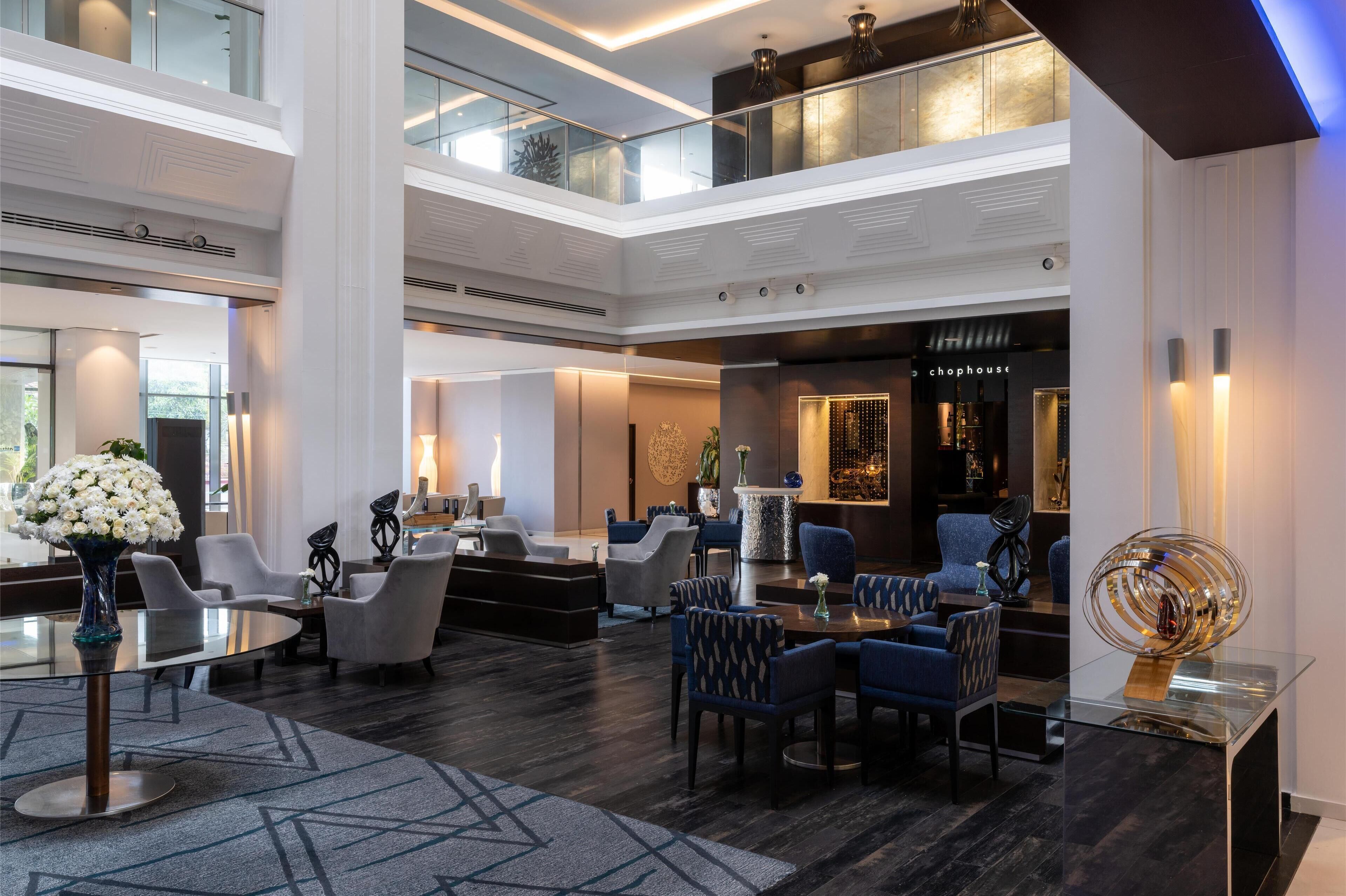 A spacious lobby with a high ceiling, multiple seating areas, and a bar/lounge area.