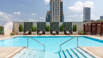 Una piscina al aire libre, sombrillas, tumbonas
