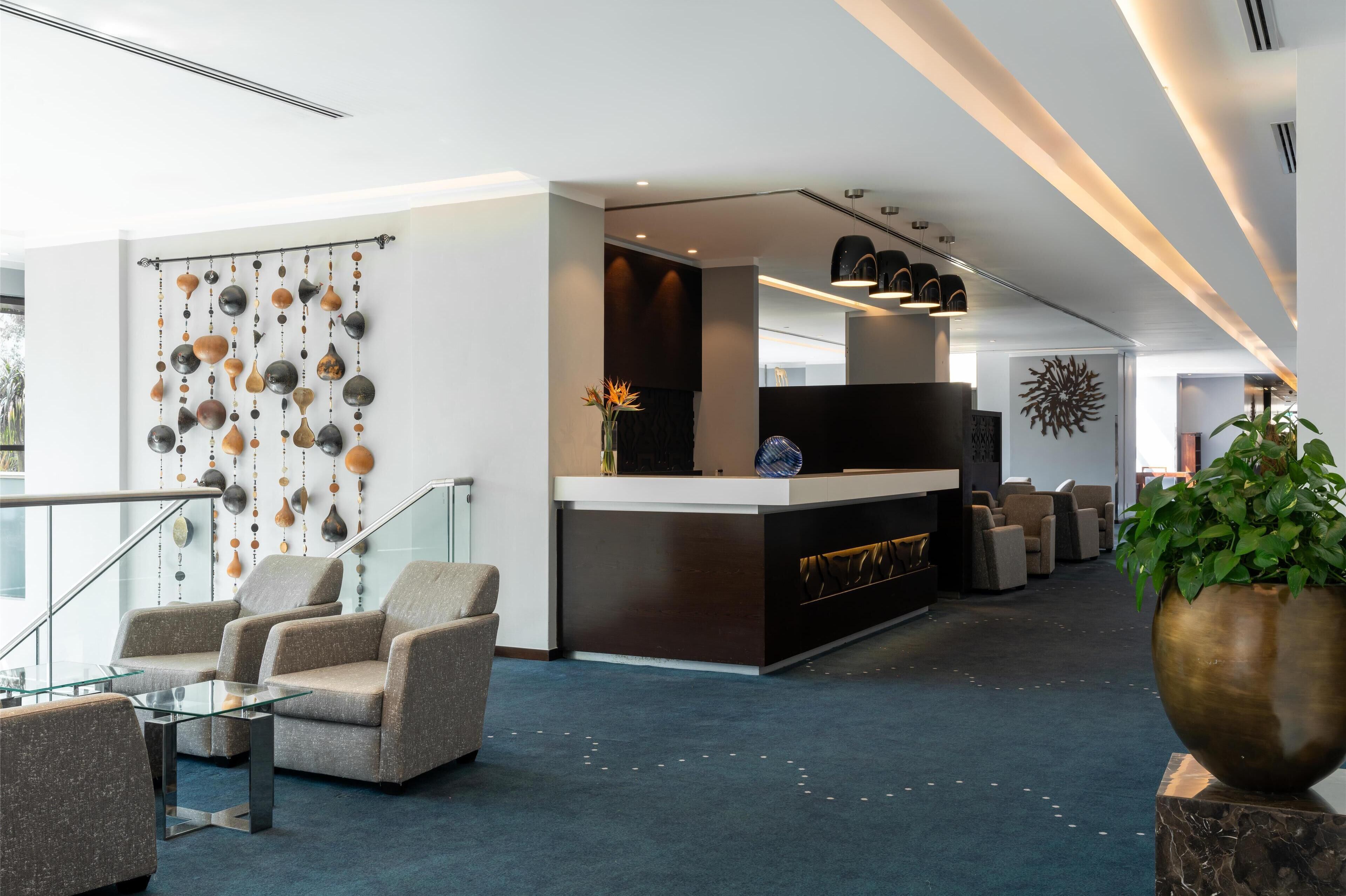 En moderne lobby med reception, siddeområde og dekorativ væg.