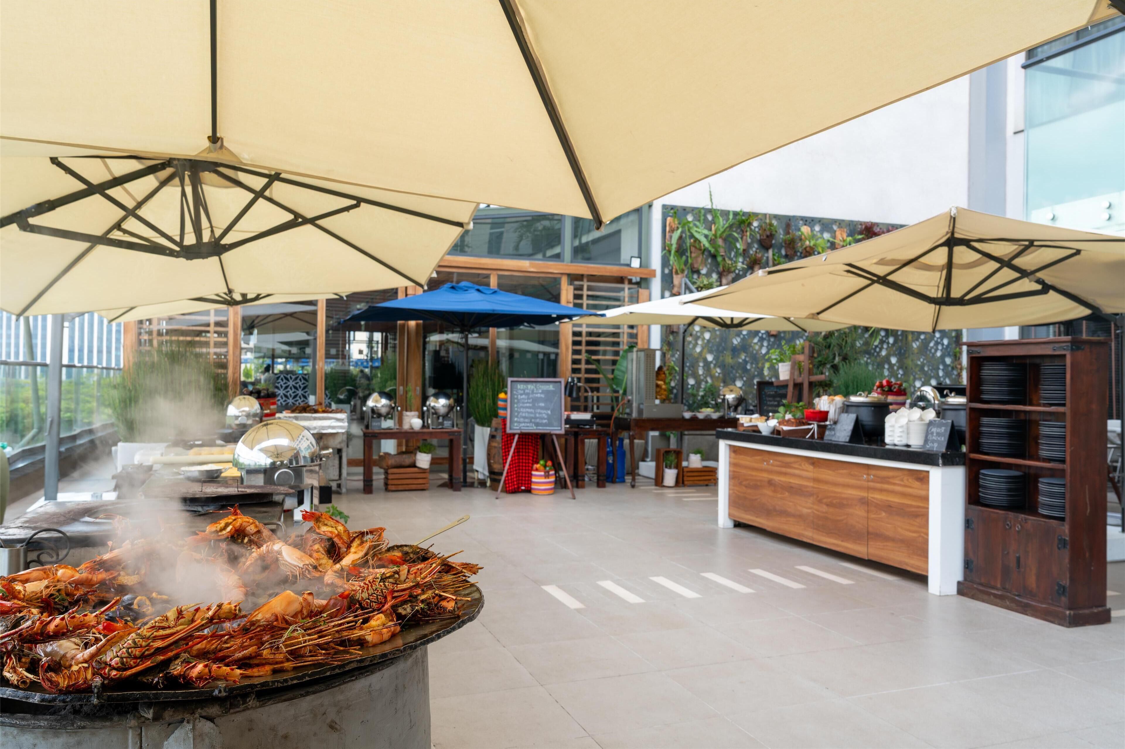 A restaurant with a grill, outdoor seating, and a view of the city.