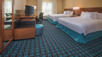 A hotel room with two beds, a desk with a TV, a chair, and a patterned carpet.
